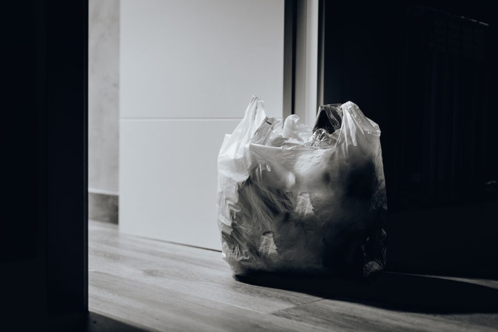 Zdjęcie przedstawia worek plastikowy wypełniony odpadami, znajdujący się w mieszkaniu. Ma to stanowić ilustrację do wpisu blogowego o tytule: "Zasady segregowania śmieci - co powinieneś wiedzieć".