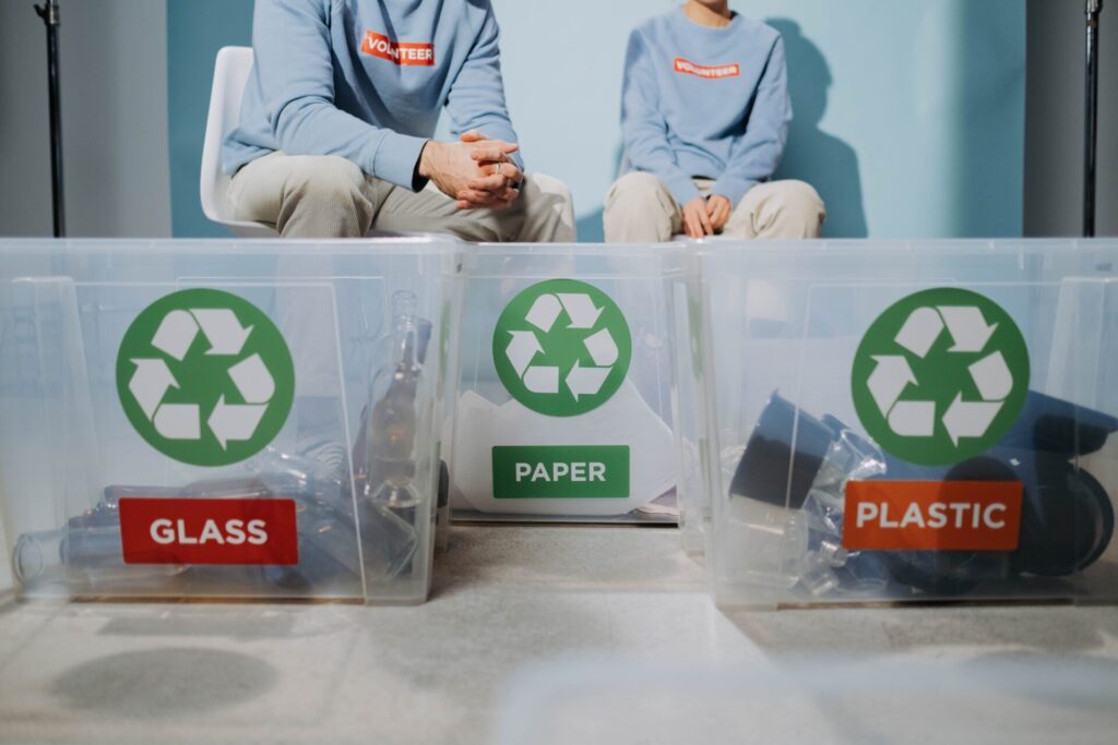 Na fotografii widzimy trzy przezroczyste pojemniki na szkło, papier, plastik. Jest to ilustracja do bloga o tytule: "Co podlega recyklingowi, a co nie?".