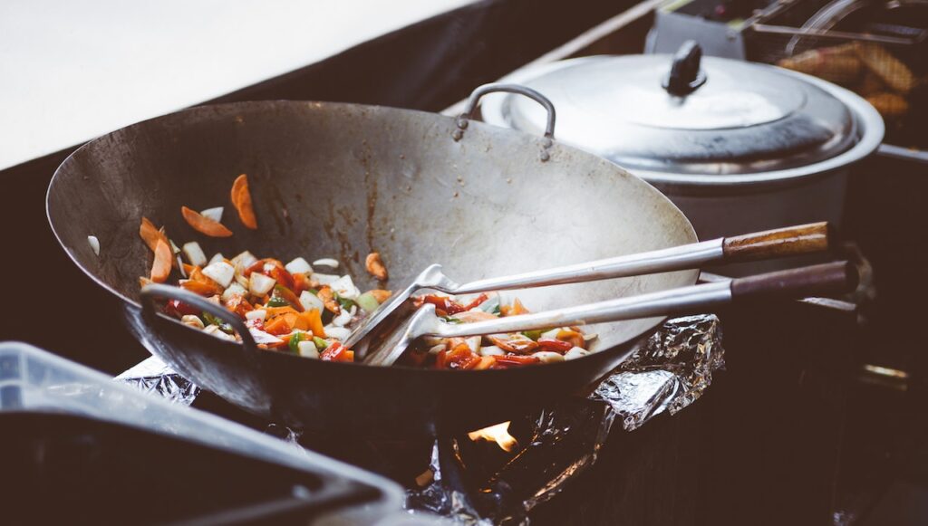 Fotografia przedstawia wok z resztką jedzenia w środku. Jest to zdjęcie, które ma ilustrować tematykę bloga o tytule: "Odpady pokonsumpcyjne - definicja, odbiór".